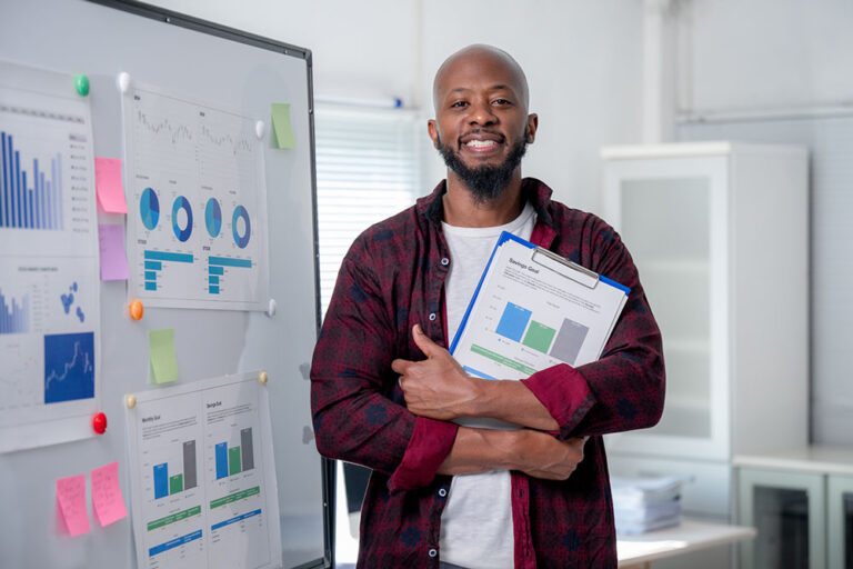 Business strategist holding research reports in an office with data charts, representing the value of human insight over AI tools.