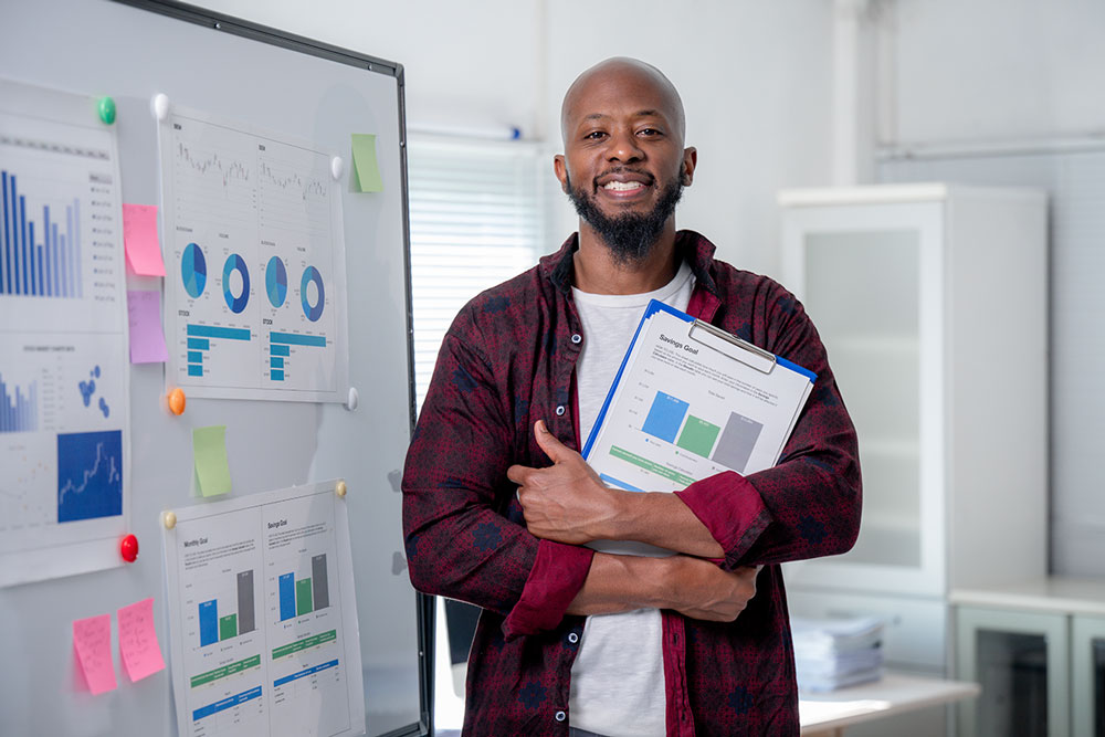 Business strategist holding research reports in an office with data charts, representing the value of human insight over AI tools.